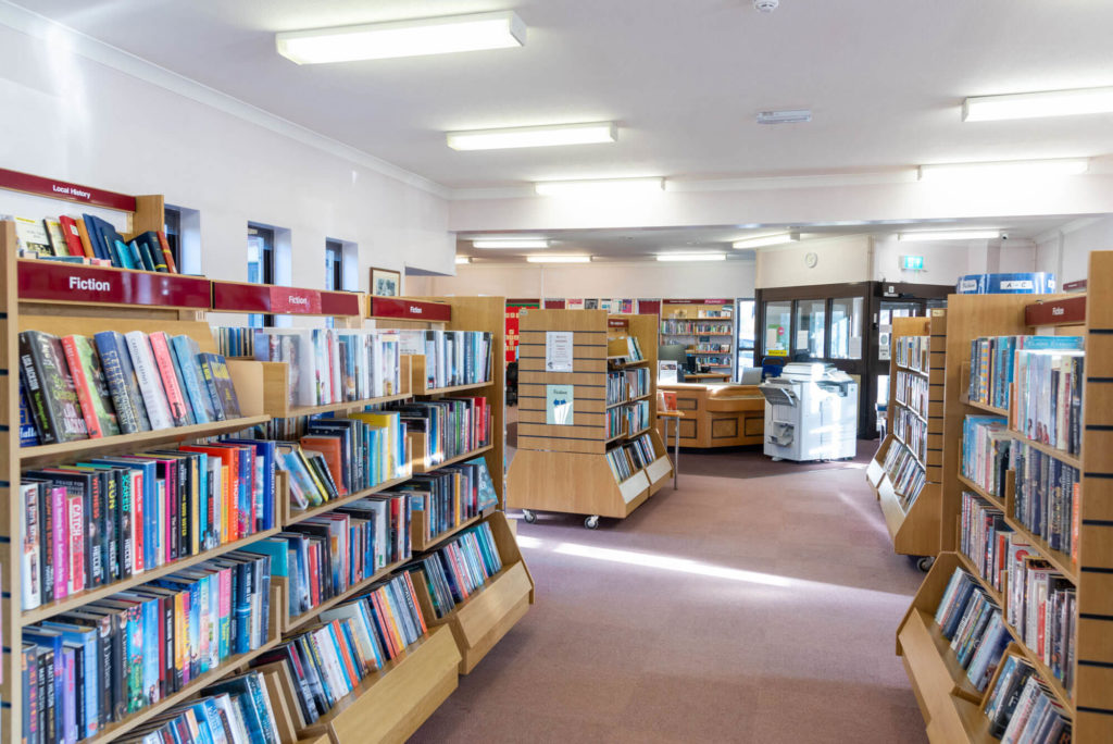 Adult fiction area at Langport Library with rows of book shelves, clearly labelled collections and open space for browsing and borrowing.