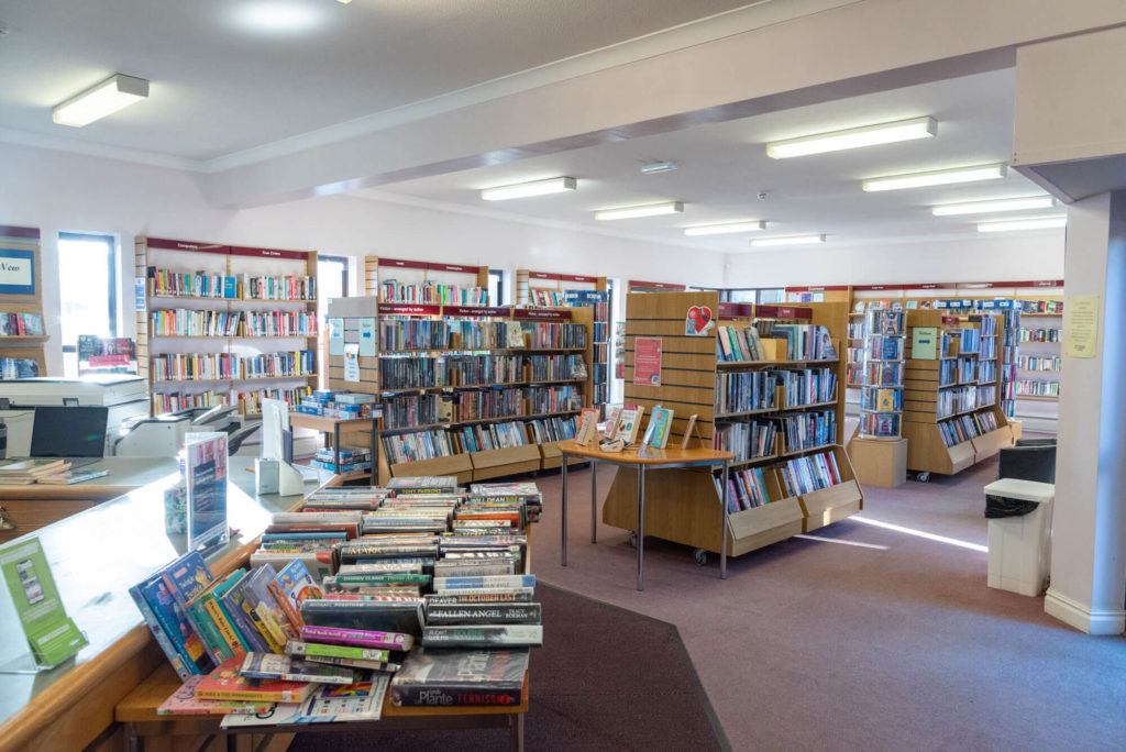 Main lending area at Langport Library with book displays, fiction shelves, customer service desk and open space for browsing and borrowing.
