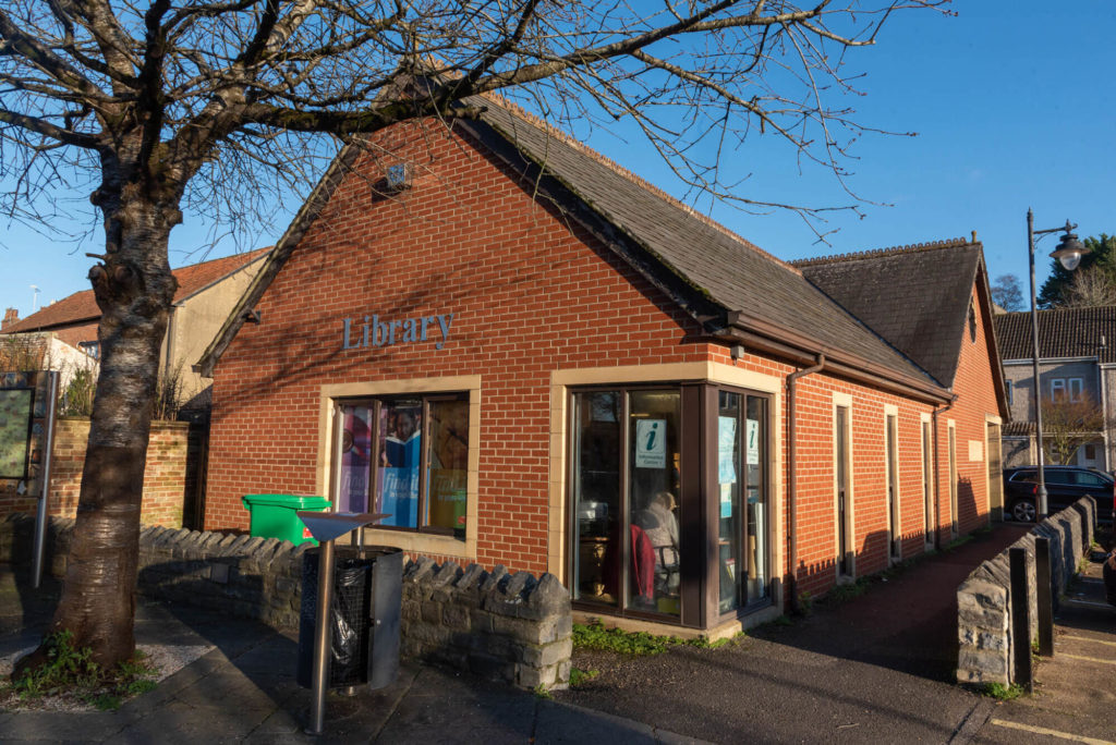 Exterior of Langport Library, a modern red-brick building with large windows, library signage and accessible pedestrian access from the street.