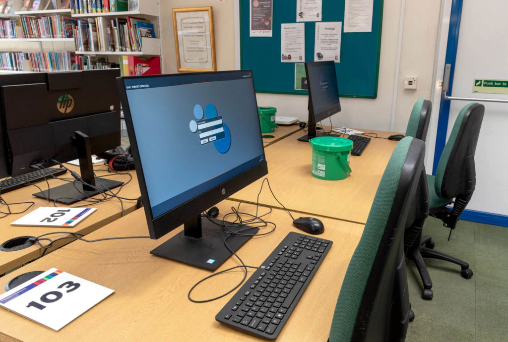 Public access computer area at Wincanton Library with desktop workstations, keyboards, numbered desks and seating for internet access, learning and online services.