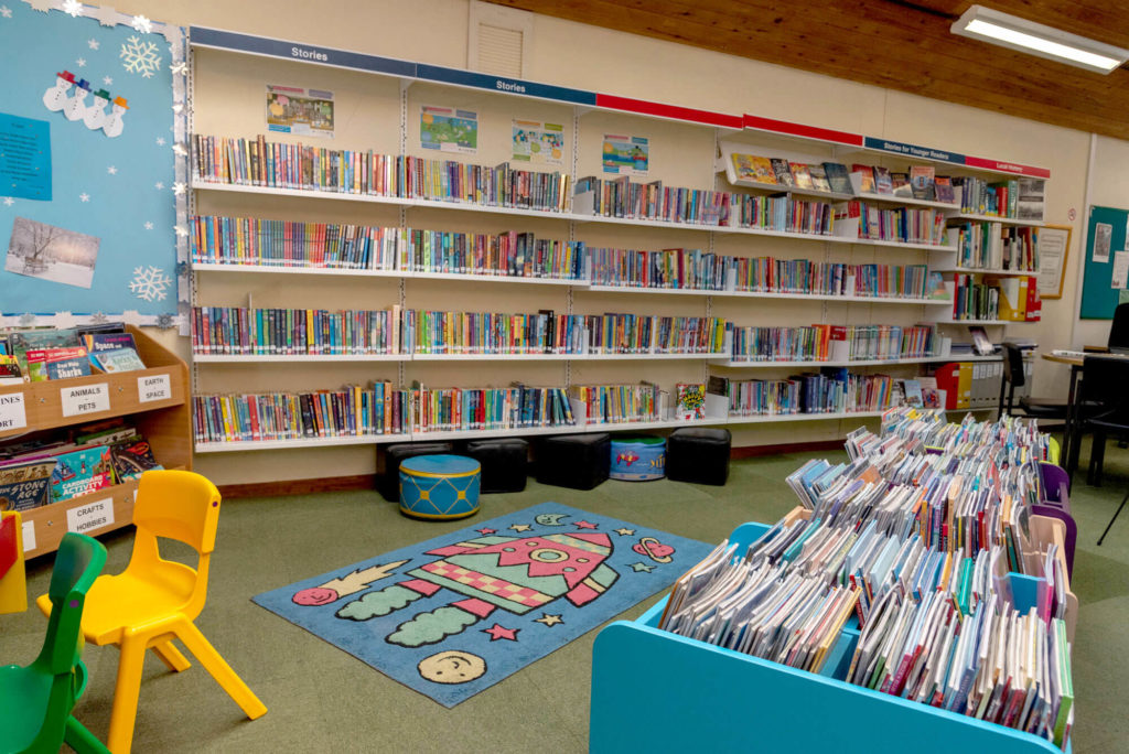 Children's area at Wincanton Library with bookshelves for younger readers, picture book displays, colourful seating, a space-themed reading rug and open space for reading and learning.