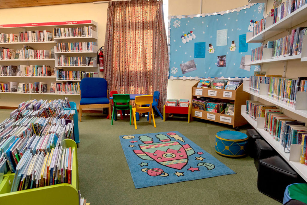 Children's library area at Wincanton Library with picture books, colourful seating and a space-themed reading rug.