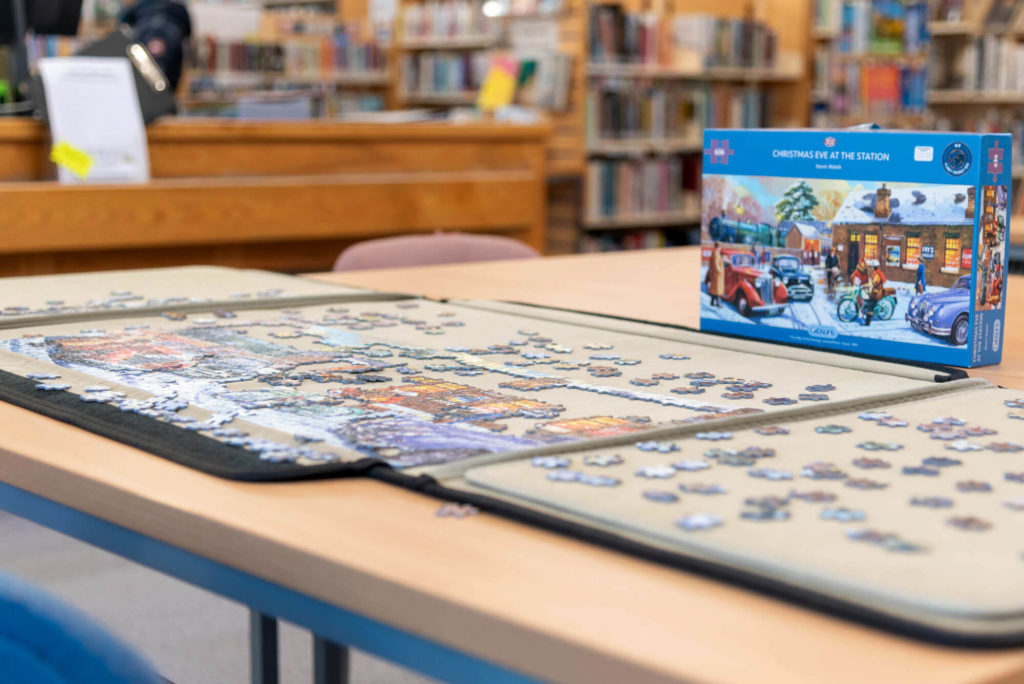 Community jigsaw puzzle in progress at Somerton Library, with a partially completed winter scene on a shared table for visitors to take part in.