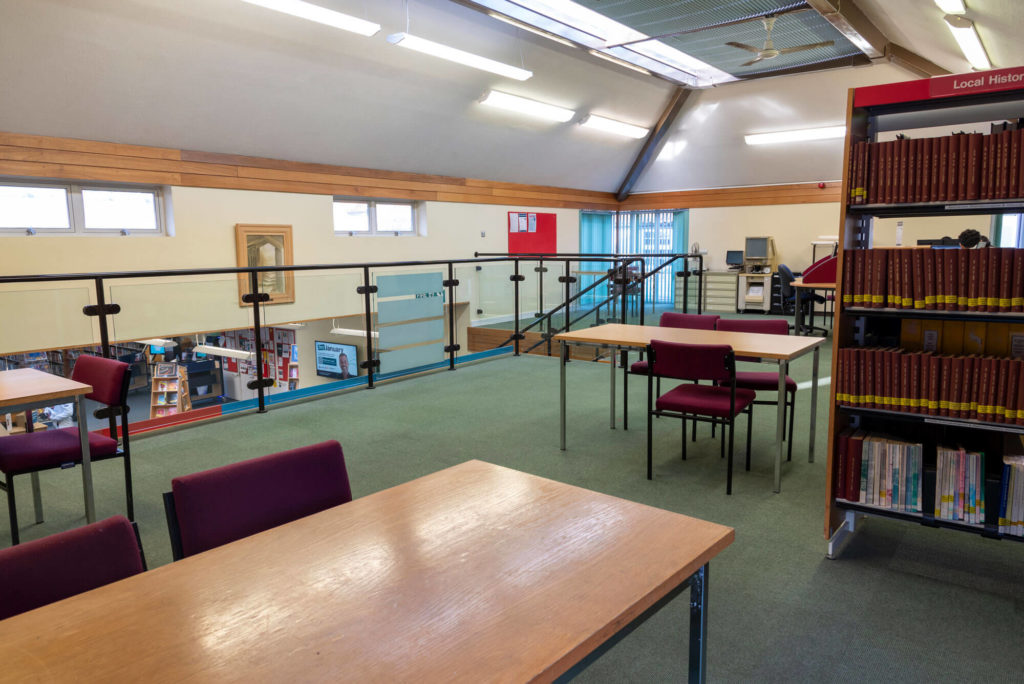 Local history and study area at Wells Library with reference book collections, study tables, seating and an upper-level workspace overlooking the main library.