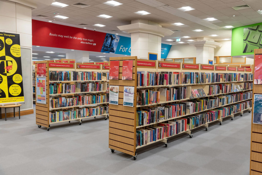 Fiction collection at Taunton Library with extensive rows of bookshelves, clearly labelled author sections and wide aisles for browsing within the main lending area.
