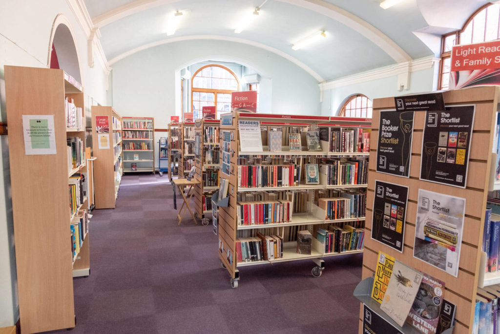 Bookshelves in a public library showing fiction titles, reading recommendations and book award displays.