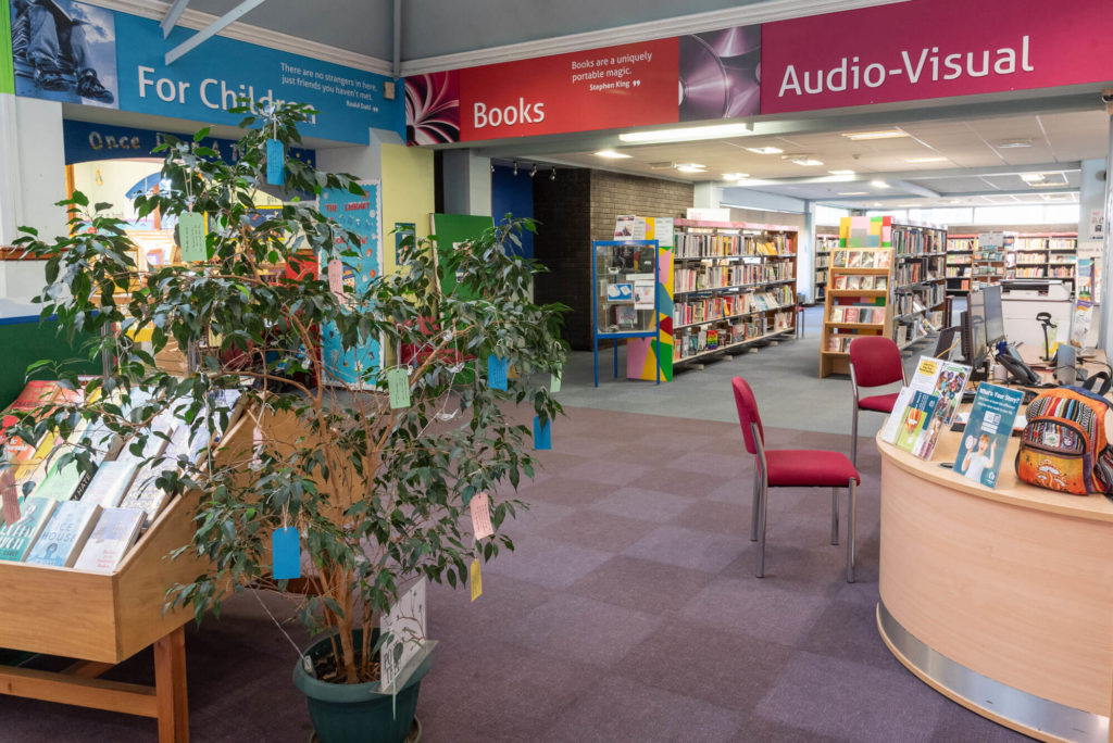 Library interior showing the children’s area, book displays, customer service desk and shelving for books and audio-visual materials.
