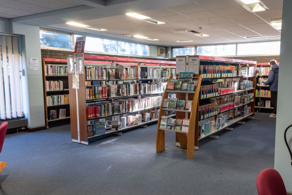 Library shelves containing non-fiction books, including history, biography and travel collections, with clear category signage.