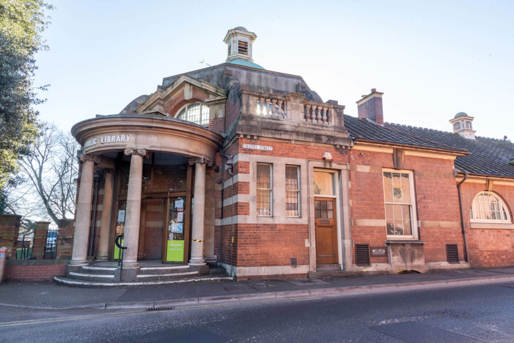 Exterior of Bridgwater Library, a historic brick building with a columned entrance and public library sign.