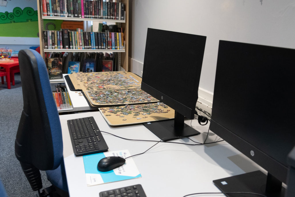 Public access computer workstations at North Petherton Library with desktop PCs, seating and nearby book collections