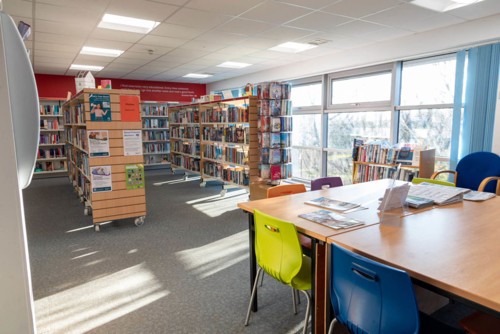 Reading and study area at Priorswood Library with book collections, study tables, colourful seating and large windows providing natural light throughout the library.