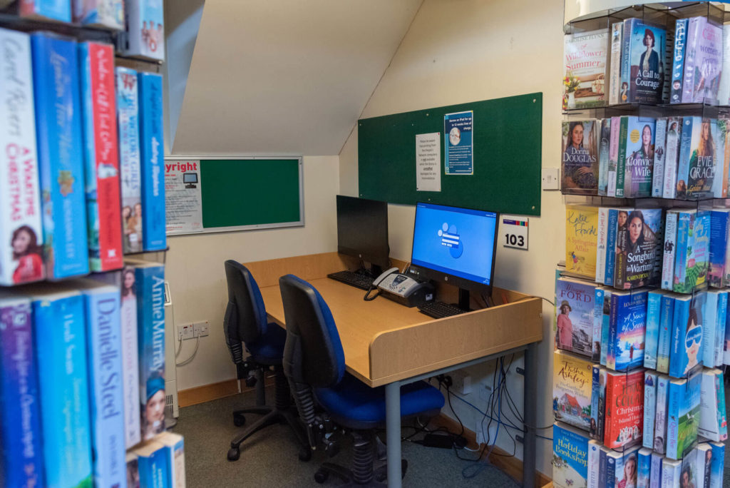 Public access computer area at Dulverton Library with desktop workstations, study seating and nearby book displays.