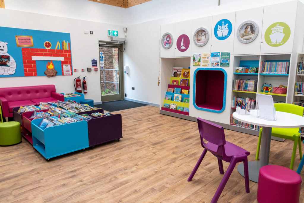 Children's area at Minehead Library with colourful book displays, reading nook, activity table, picture books and bright seating for young readers and families.