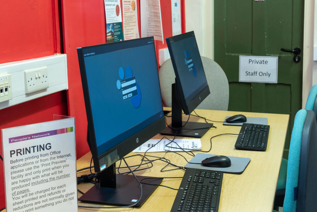 Public access computer area at Porlock Library with desktop workstations, seating and facilities for internet access, printing and online services.