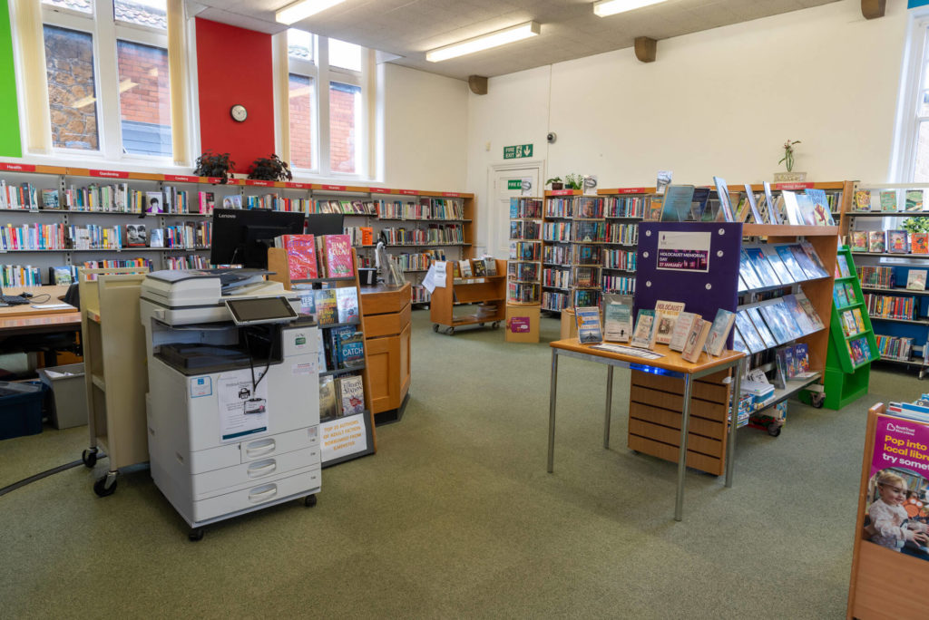 Main library area at Ilminster Library with book shelves, featured displays, customer service desk and a bright open space for browsing and borrowing.