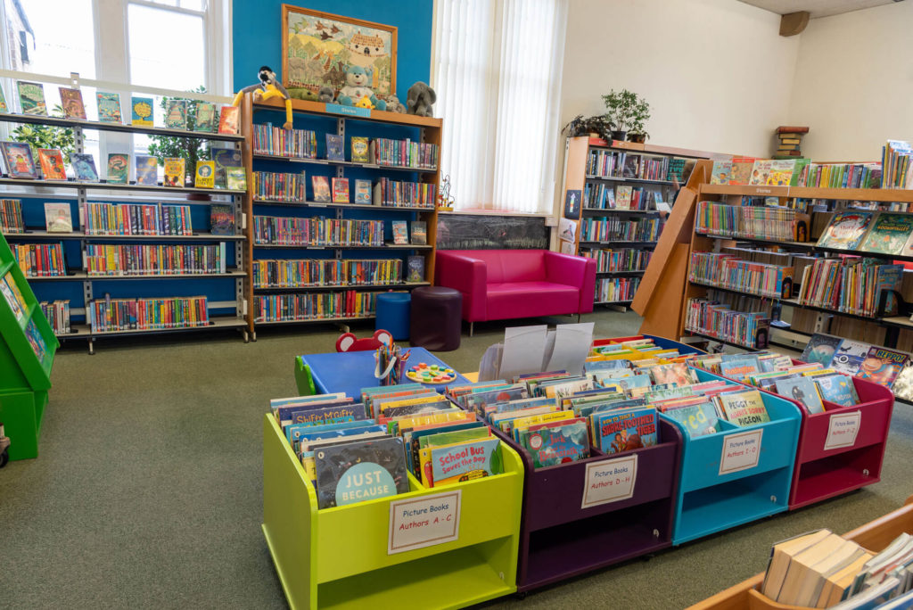 Children's area at Ilminster Library with colourful picture book displays, children's bookshelves, activity table and seating for young readers and families.