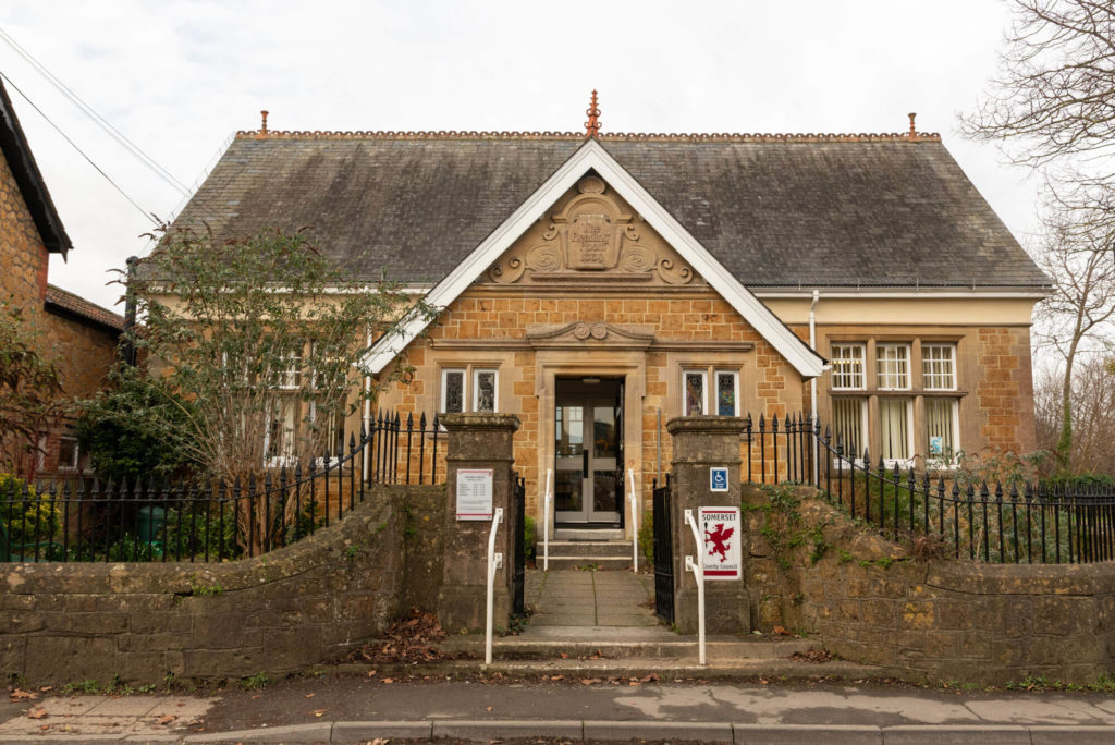 Exterior of Ilminster Library, a historic stone building with decorative architectural details, accessible entrance and railings along the front boundary.