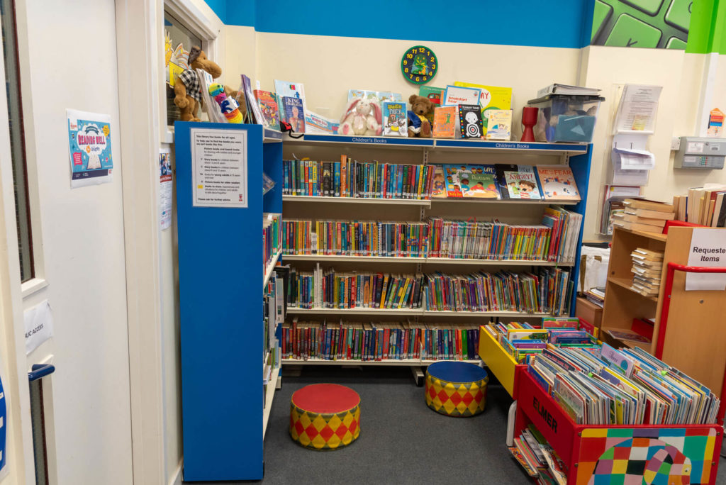 Children's area at Wiveliscombe Library with shelves of children's books, picture book displays, colourful seating and browsing space for young readers and families.