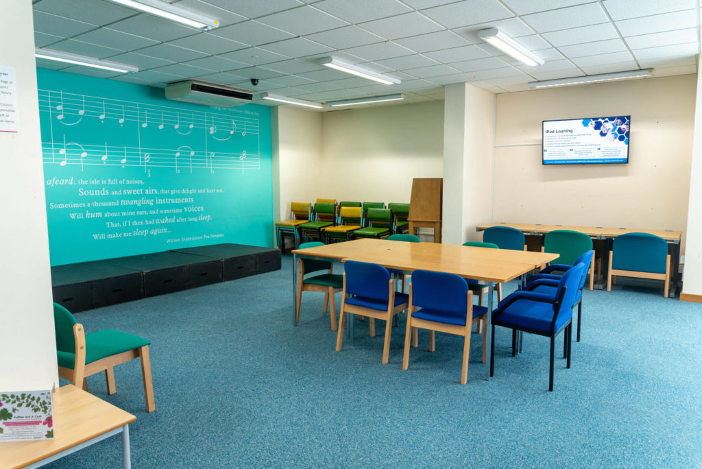Community meeting and event space at Yeovil Library with tables, seating, a small presentation stage and flexible layout for workshops, group activities and library events.