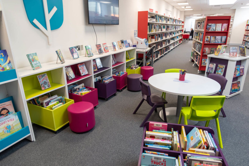 Children's area at Wellington Library with colourful book storage, activity table, children's seating and shelves of books for reading, learning and family activities.