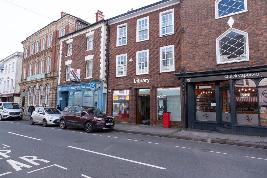 Exterior of Wellington Library, a town-centre brick building with large front windows, library signage and an accessible entrance on the high street.