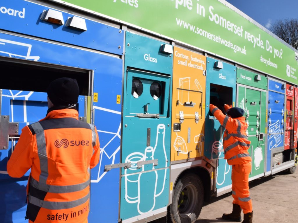 People in high visibility uniform loading recycling into a truck