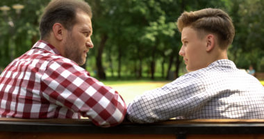Man and boy sitting on a bench talking