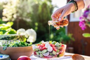 Bottle of oil being poured onto a bowl of salad