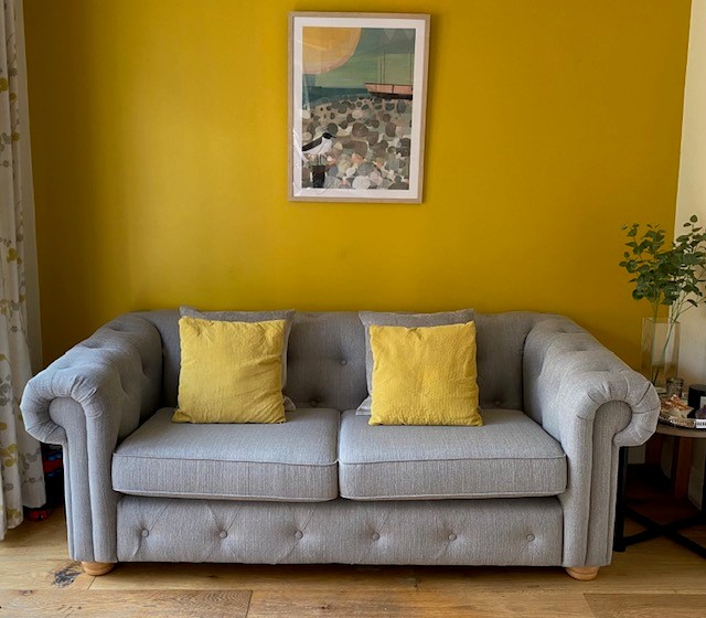 picture of a grey sofa with yellow cushions in a yellow living room