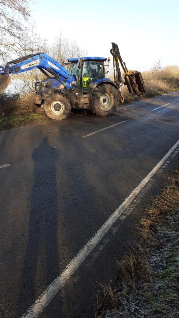 Blue tractor working on a road verge