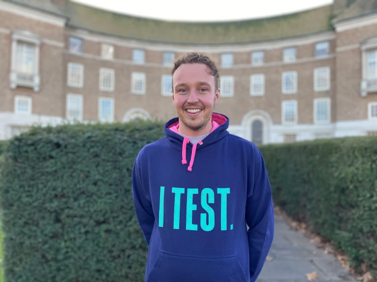 A photo of a man wearing a hoodie with the words I test on the front