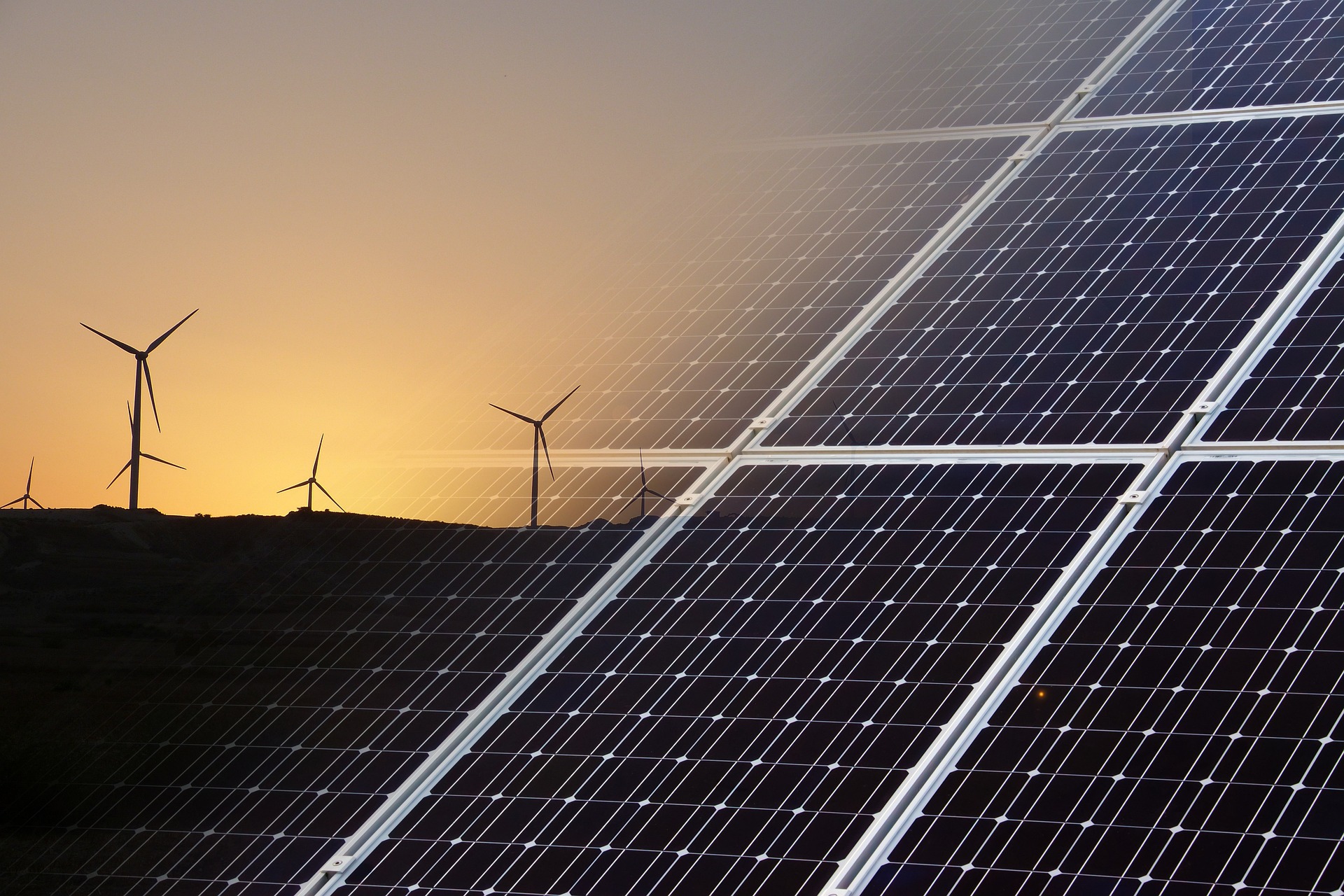 photograph of wind turbines at sunset and solar panels