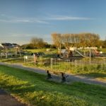 Fenced play area with climbing frame, slide and swings