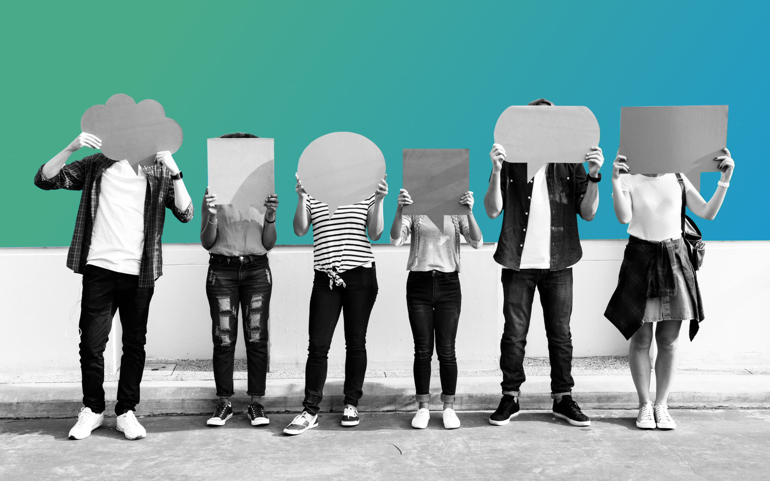 Group of people stood together holding different sized quote shapes