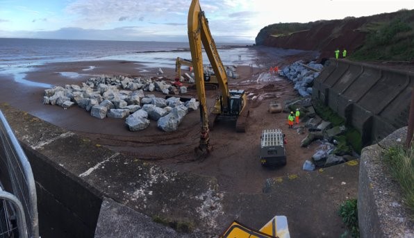 Heavy machinery moving rock on beach