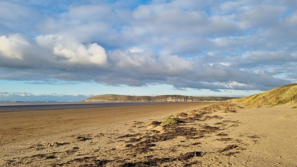 Brean Sands beach with dunes and wide shoreline under dramatic skies on the Somerset coast.