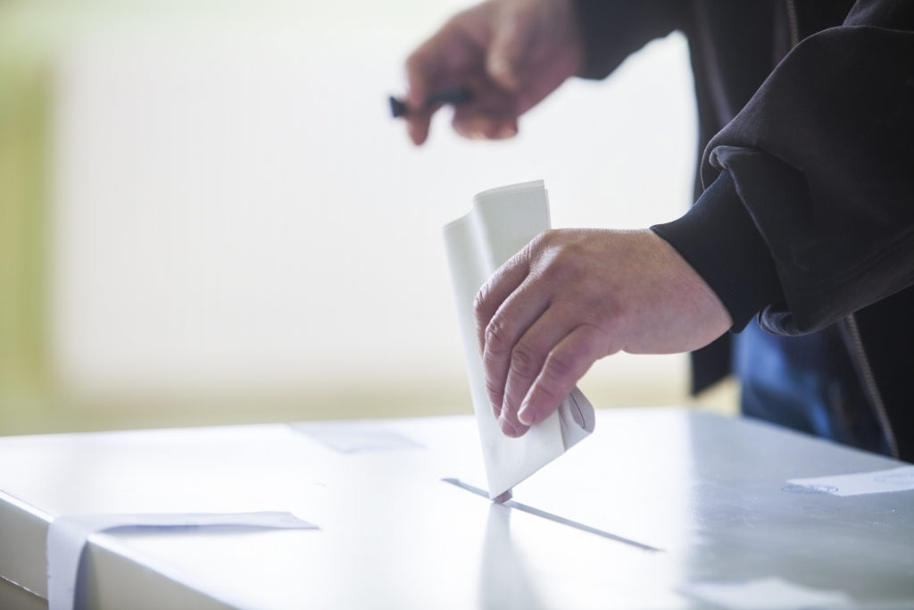 Hand dropping ballot paper into ballot box