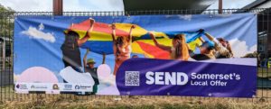 Horizontal banner with image of children playing parachute games, and SEND Partnership branding including partners logos, and a QR code to go to the Local Offer website.