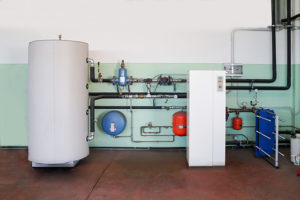 A ground source heat pump. It is a large tank connected to pipes which are mounted on an interior wall