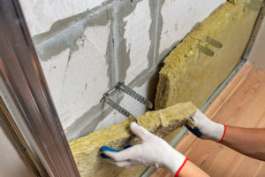 A worker wearing protective gloves installing wall insulation