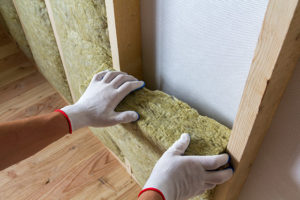 A worker wearing protective gloves installing internal wall insulation