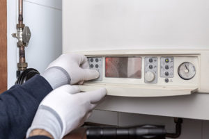 A heating engineer performing a boiler service with gloves on
