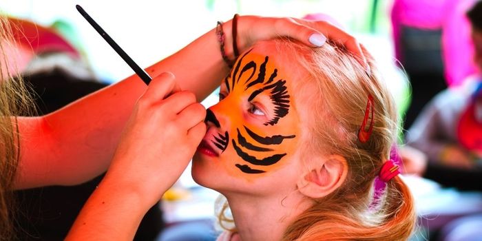 Girl having her face painted as a tiger