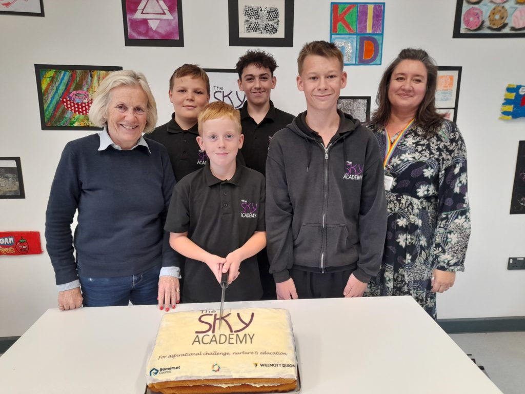 Tessa Munt cutting cake with students from school