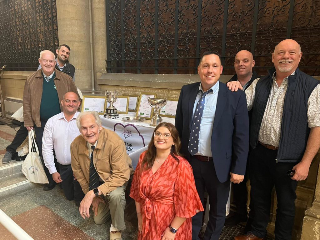 A group shot of people standing in front of a table with the awards on it.