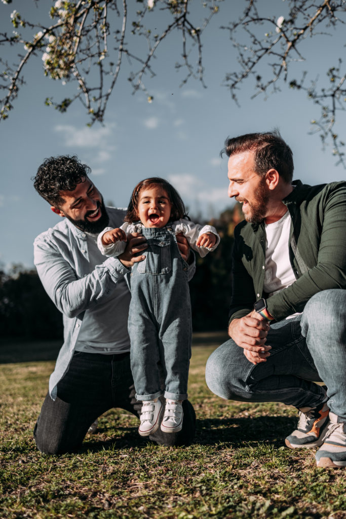 Male gay couple take care of their little daughter in a park