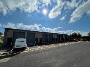 View of the units with sectional doors. There are marked spaces for parking and loading outside.