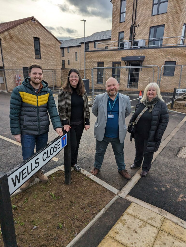 Four people stood in a row at a new housing development site.