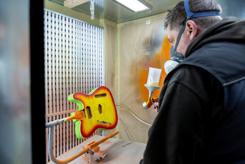 Man spray painting body of guitar