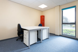 Wells small office space. There are two desks facing each other and a large floor to ceiling window.